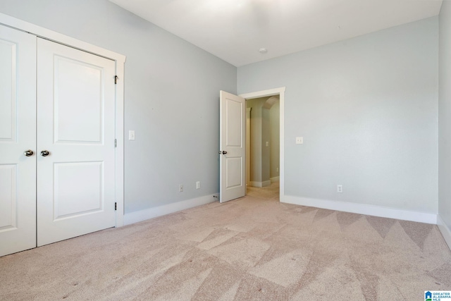 unfurnished bedroom with a closet, baseboards, and carpet
