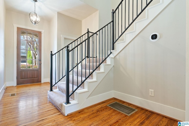 foyer entrance featuring stairs, light wood-style floors, visible vents, and baseboards