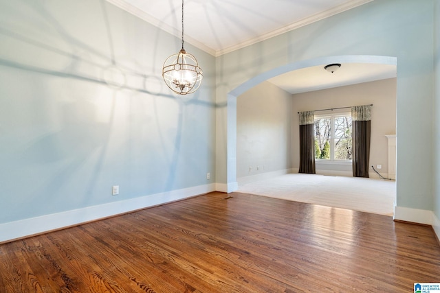 empty room featuring arched walkways, baseboards, and wood finished floors