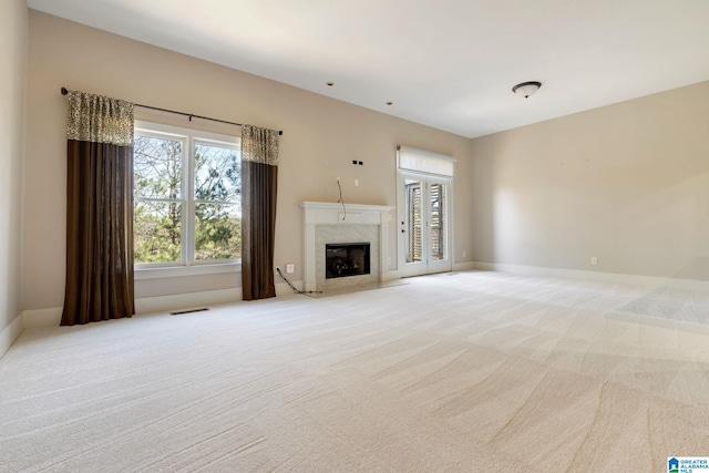 unfurnished living room featuring visible vents, a fireplace, baseboards, and light carpet