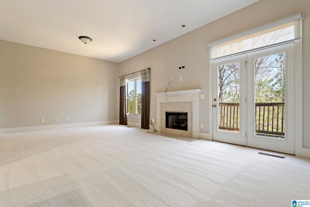 unfurnished living room with carpet flooring, baseboards, visible vents, and a premium fireplace