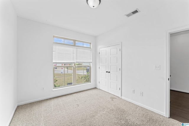 unfurnished bedroom with carpet, visible vents, a closet, and baseboards