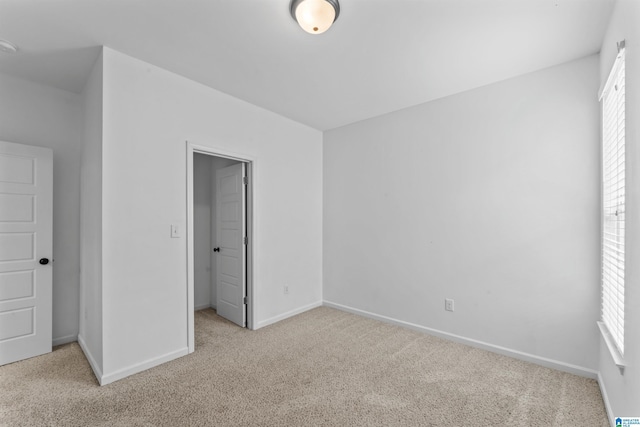 unfurnished bedroom with carpet, a spacious closet, and baseboards