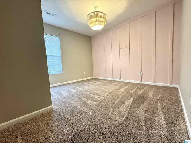 unfurnished bedroom featuring visible vents, baseboards, a chandelier, carpet floors, and a textured ceiling