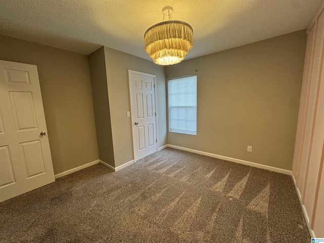 unfurnished bedroom with a textured ceiling, baseboards, carpet floors, and a chandelier