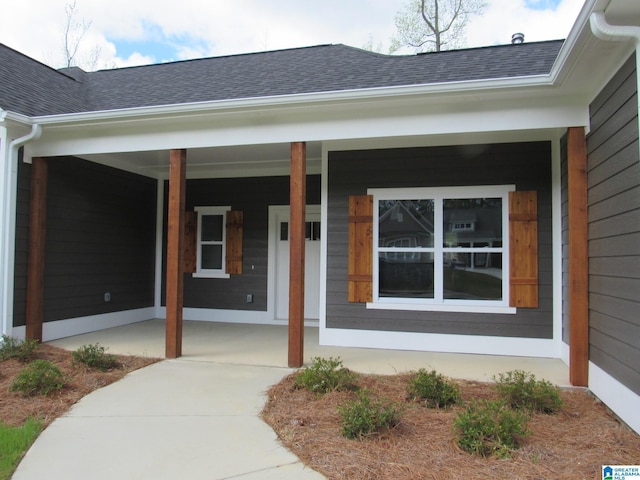 doorway to property with covered porch and roof with shingles