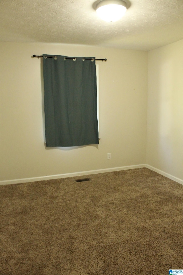 carpeted spare room featuring a textured ceiling, baseboards, and visible vents