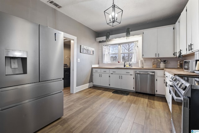 1109 Central Ave, Gadsden, AL 35904 - kitchen featuring visible vents, appliances with stainless steel finishes, light wood-style flooring, and white cabinets