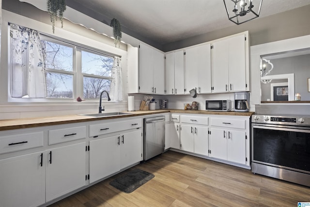 1109 Central Ave, Gadsden, AL 35904 - kitchen with light wood-style flooring, a sink, stainless steel appliances, white cabinets, and a chandelier