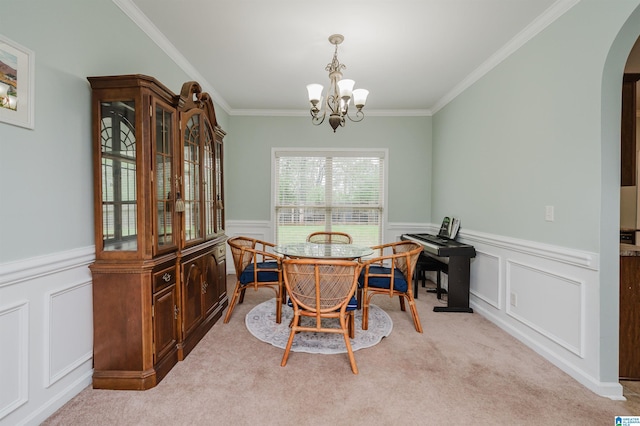 carpeted dining area with arched walkways, an inviting chandelier, and a wainscoted wall