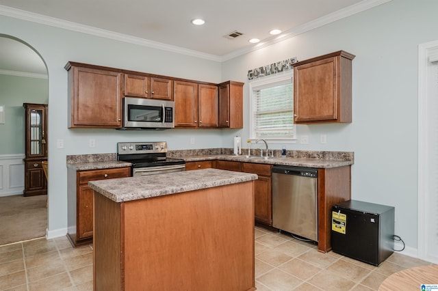 kitchen featuring ornamental molding, visible vents, a center island, appliances with stainless steel finishes, and a sink