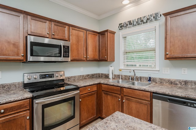 kitchen featuring stainless steel appliances, brown cabinetry, a sink, and ornamental molding