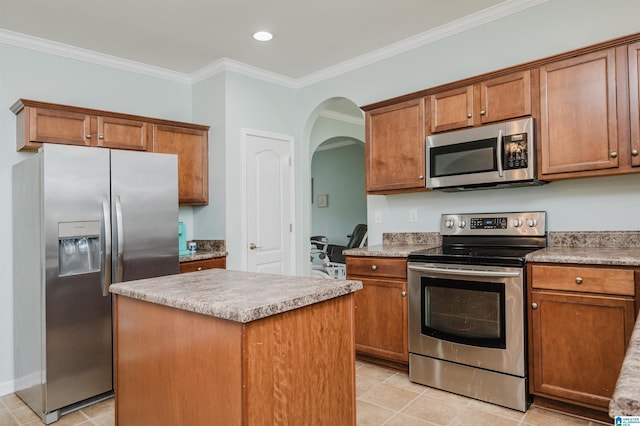 kitchen with ornamental molding, a center island, brown cabinetry, appliances with stainless steel finishes, and arched walkways
