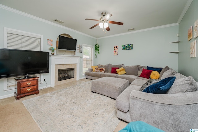 living room featuring a tiled fireplace, visible vents, ornamental molding, and ceiling fan