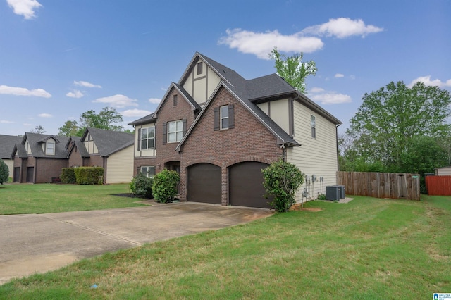 tudor-style house with concrete driveway, a front yard, fence, and an attached garage