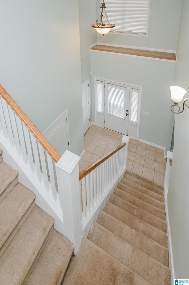 stairs with tile patterned flooring, a high ceiling, and baseboards