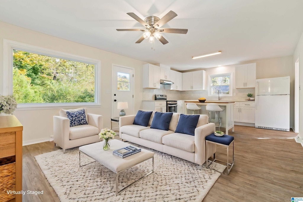 living room with light wood finished floors, baseboards, and a ceiling fan