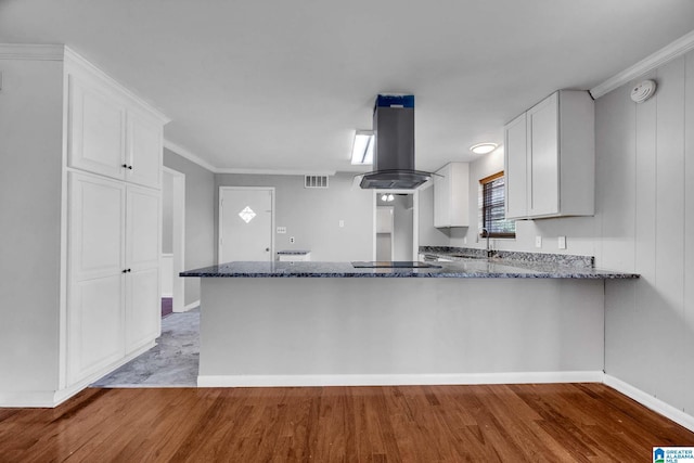 817 Milgray Ln, Bessemer, AL 35022 - kitchen with dark stone countertops, a peninsula, island exhaust hood, and white cabinetry