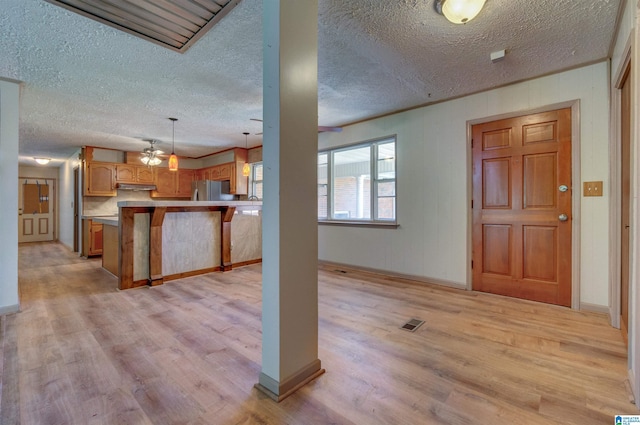 foyer with visible vents, a textured ceiling, ornamental molding, and light wood finished floors