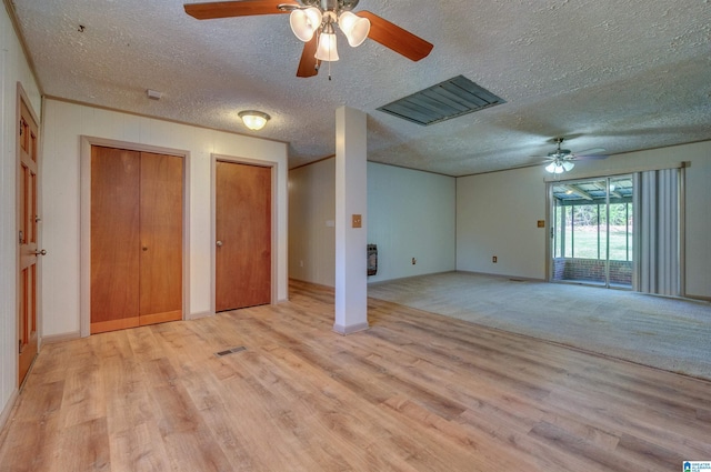 unfurnished bedroom with visible vents, light wood finished floors, ceiling fan, multiple closets, and a textured ceiling