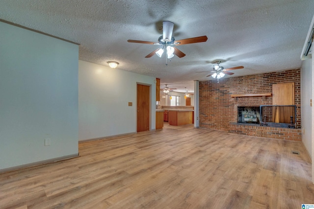 unfurnished living room with light wood-style floors, a brick fireplace, a ceiling fan, and a textured ceiling