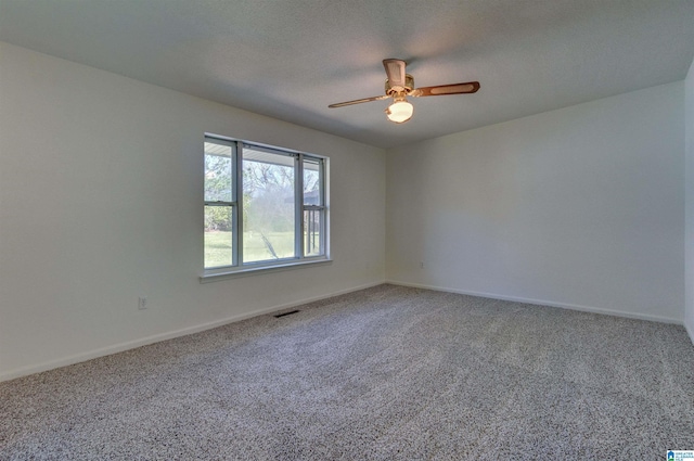 carpeted empty room featuring visible vents, a textured ceiling, baseboards, and ceiling fan