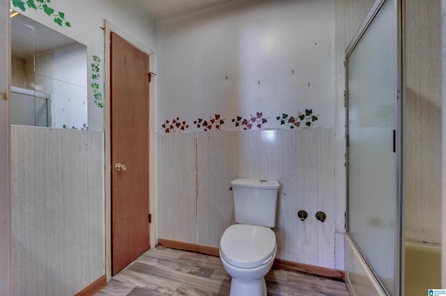full bathroom with enclosed tub / shower combo, toilet, and wood finished floors