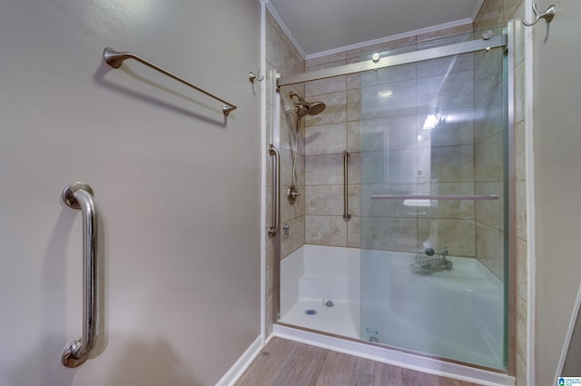 full bathroom featuring a shower stall, a textured ceiling, crown molding, and wood finished floors