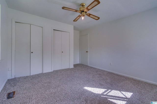 unfurnished bedroom featuring visible vents, multiple closets, carpet floors, and ceiling fan
