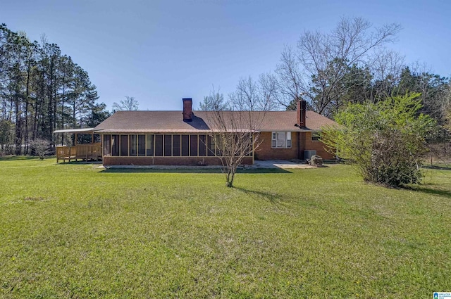 rear view of property featuring a yard, central AC, a chimney, and a sunroom