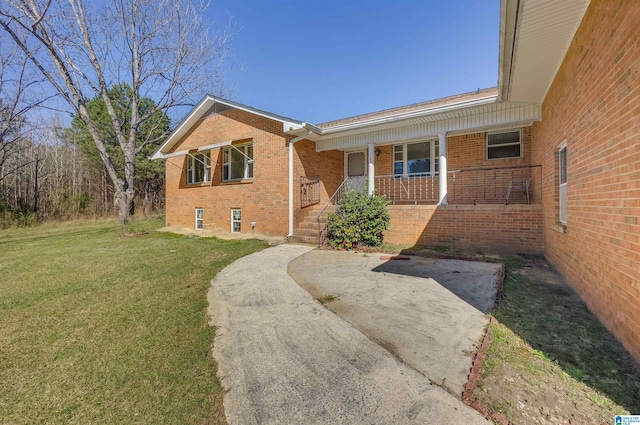 view of front of house with a porch, brick siding, and a front yard