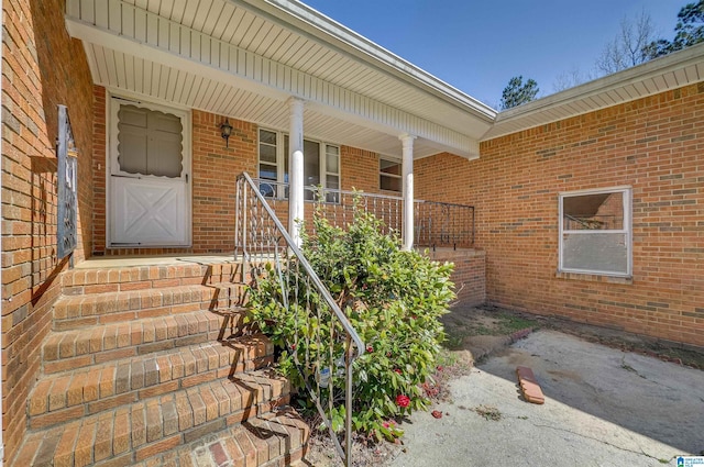 doorway to property featuring brick siding and a porch