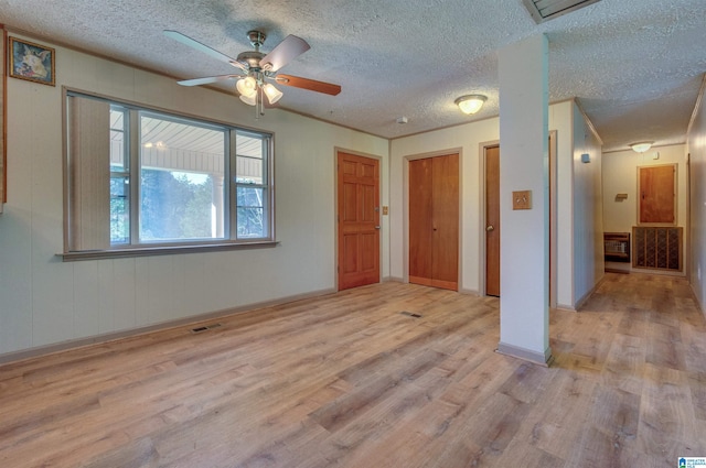 spare room featuring a ceiling fan, wood finished floors, visible vents, and a textured ceiling