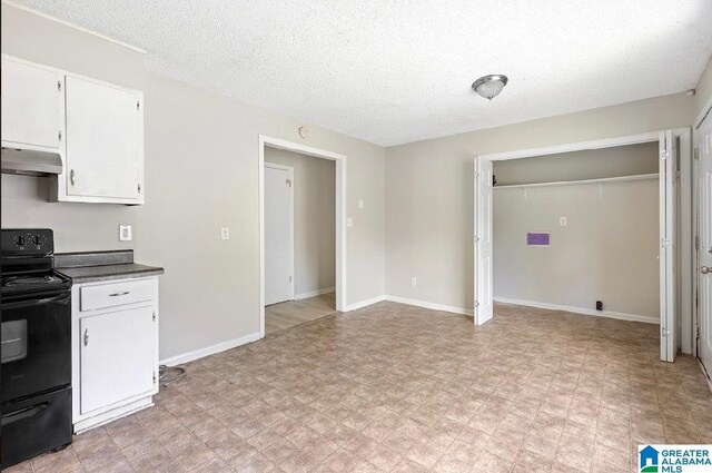 63 Bluebell St, Bessemer, AL 35020 - kitchen with baseboards, under cabinet range hood, light floors, white cabinetry, and black / electric stove
