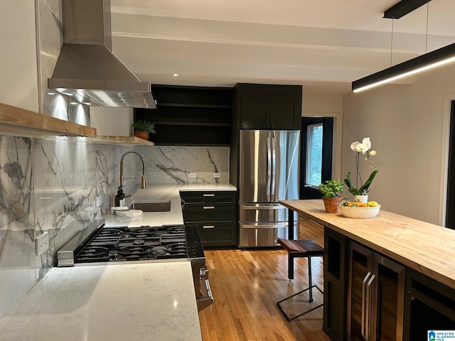 kitchen with wall chimney exhaust hood, tasteful backsplash, a sink, open shelves, and freestanding refrigerator
