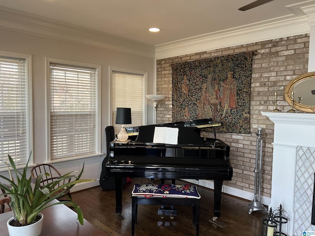 sitting room featuring crown molding, wood finished floors, baseboards, and brick wall