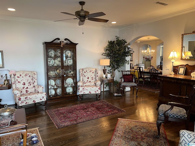 living room with visible vents, ornamental molding, ceiling fan with notable chandelier, wood finished floors, and arched walkways