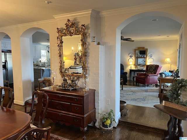 hallway with arched walkways, crown molding, and wood finished floors