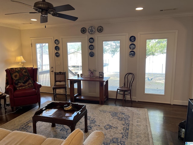 living area with a healthy amount of sunlight, wood finished floors, a ceiling fan, and ornamental molding