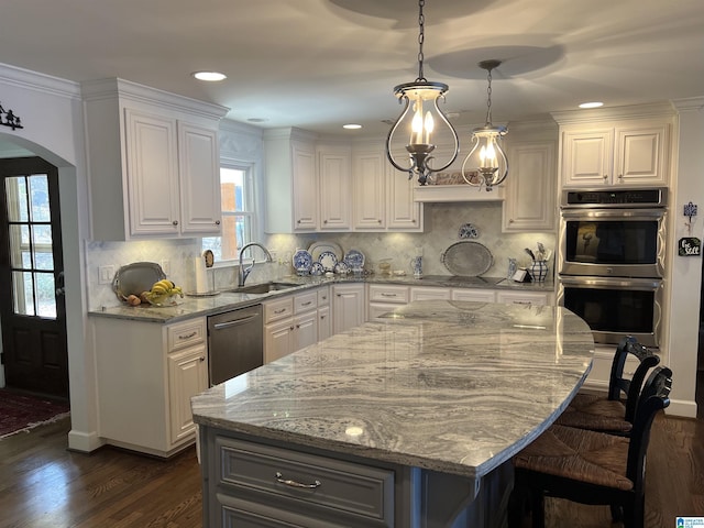 kitchen with white cabinets, light stone counters, appliances with stainless steel finishes, and a sink