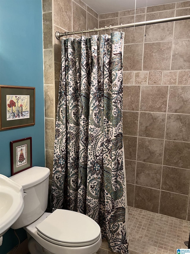 bathroom with a sink, toilet, and tiled shower