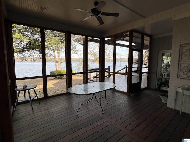 unfurnished sunroom with a ceiling fan, a water view, and a healthy amount of sunlight