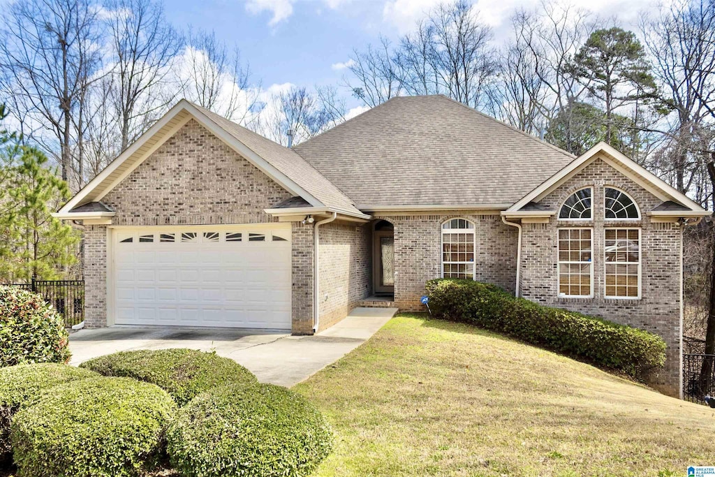 ranch-style home with driveway, roof with shingles, a front yard, a garage, and brick siding