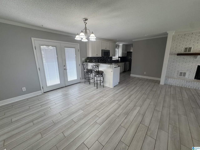 1804 Ragsdale Rd, Cullman, AL 35055 - kitchen featuring a peninsula, white cabinetry, stainless steel microwave, open floor plan, and a kitchen bar