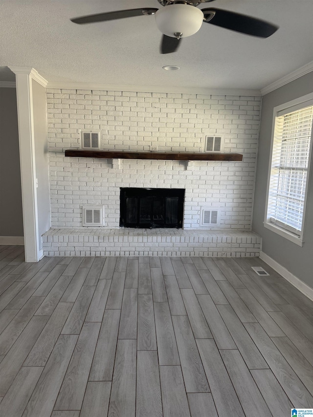 1804 Ragsdale Rd, Cullman, AL 35055 - unfurnished living room featuring a ceiling fan, visible vents, wood finish floors, crown molding, and a brick fireplace