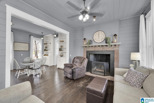 living room featuring a ceiling fan, dark wood-type flooring, a fireplace, and wooden ceiling
