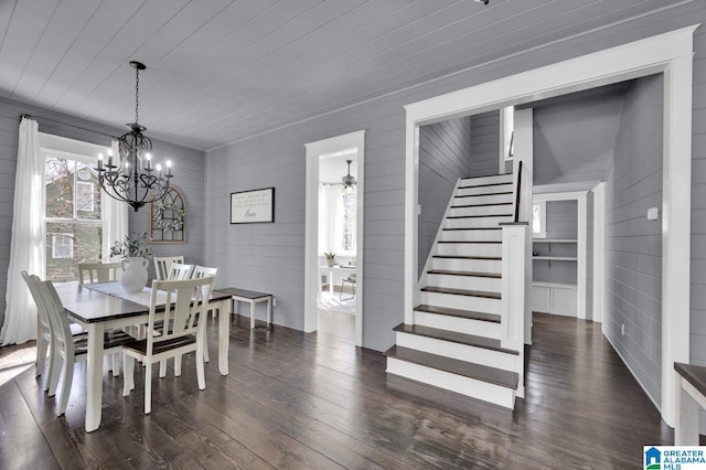 dining room with dark wood-style floors, stairway, and an inviting chandelier