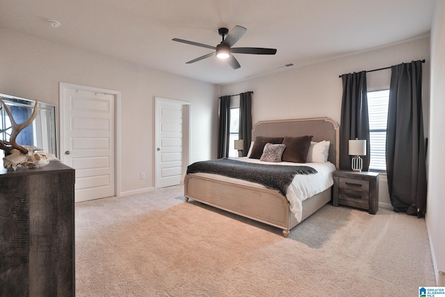 carpeted bedroom featuring multiple windows, visible vents, ceiling fan, and baseboards