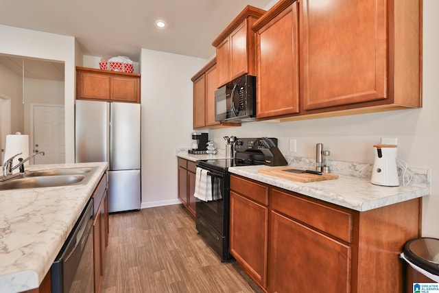kitchen featuring black appliances, wood finished floors, light countertops, and a sink