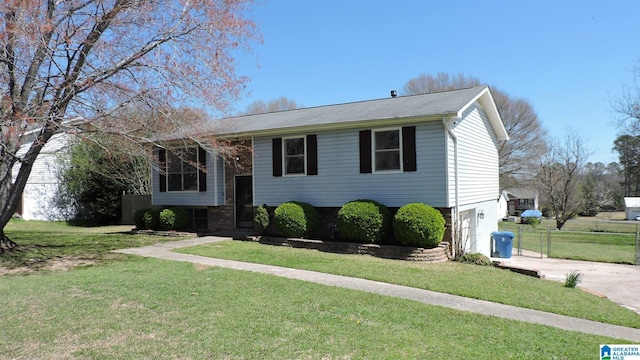 split foyer home with a front yard, concrete driveway, and an attached garage